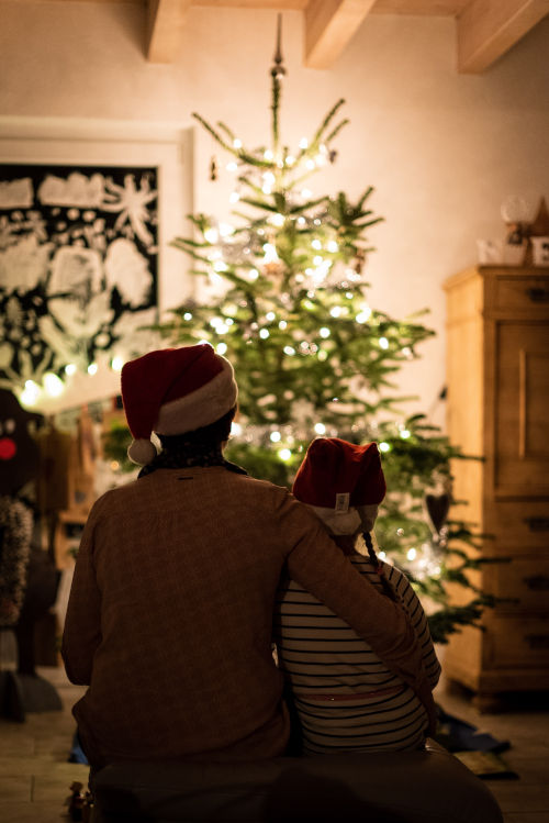 Siblings hugging in front of a holiday tree